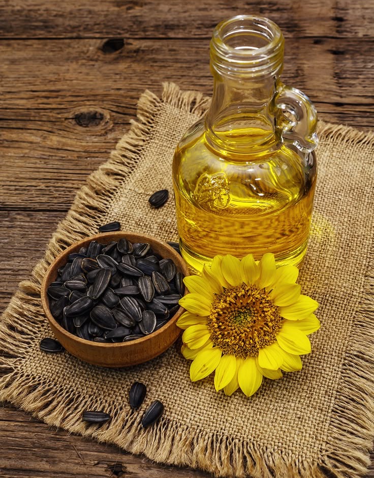 Bottle of sunflower oil beside sunflower seeds and a sunflower
