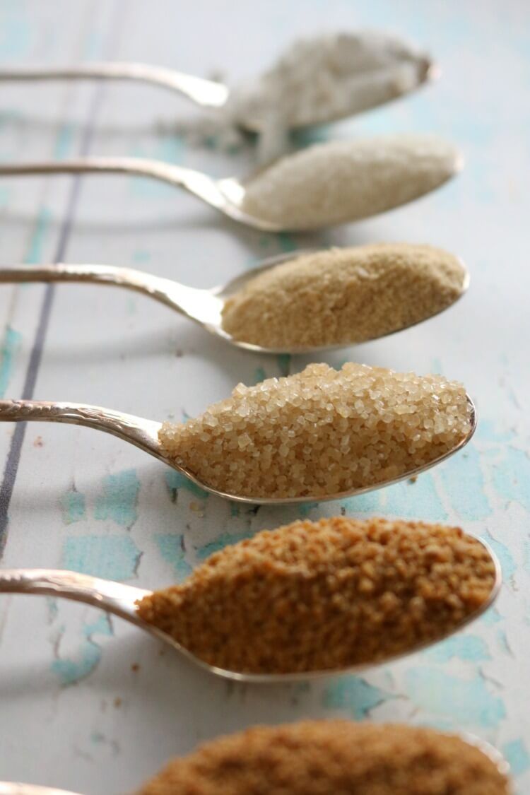 Spoons of brown sugar on a pale table